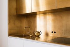 10 a polished gold kitchen backsplash and upper cabinets create a glam minimalist look in the white kitchen