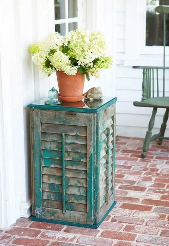 an outdoor side table of old shutters and a couple of wooden planks, the aged look fo the shutters is highlighted