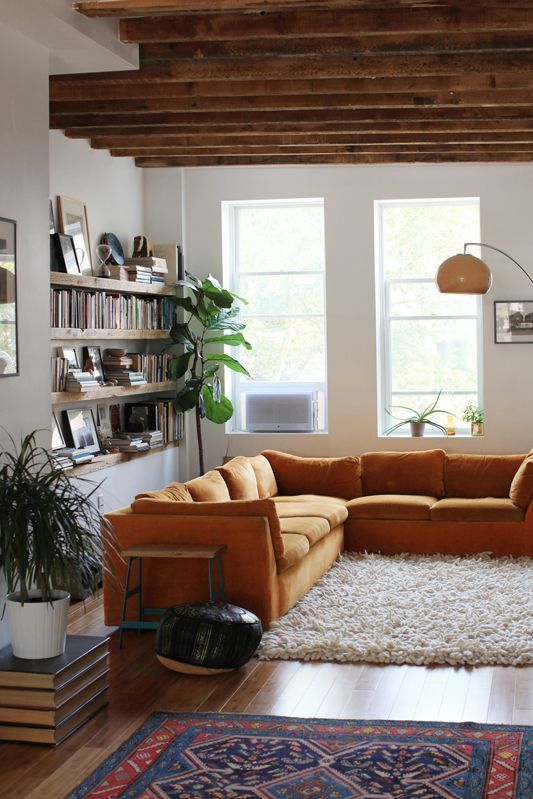 a mustard-colored L-shaped sofa brings warmth to the space and matches the rustic feel