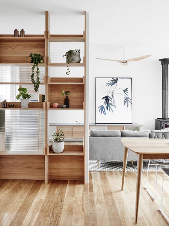 a wooden shelving unit with glass parts to separate the dining and living rooms