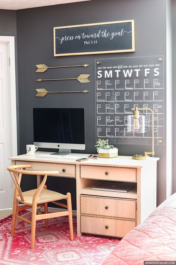 a chalkboard wall with an acrylic calendar, a sign and some gold arrows