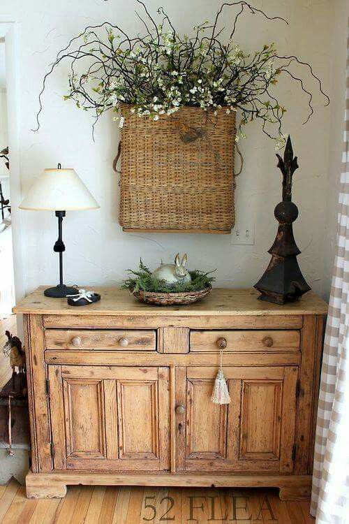 a rustic wooden console with a basket with greenery and a bunny, a basket with blooming branches in it