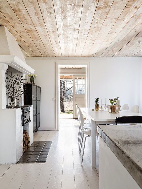 a light colored wooden ceiling adds warmth to this white space and makes it cozier