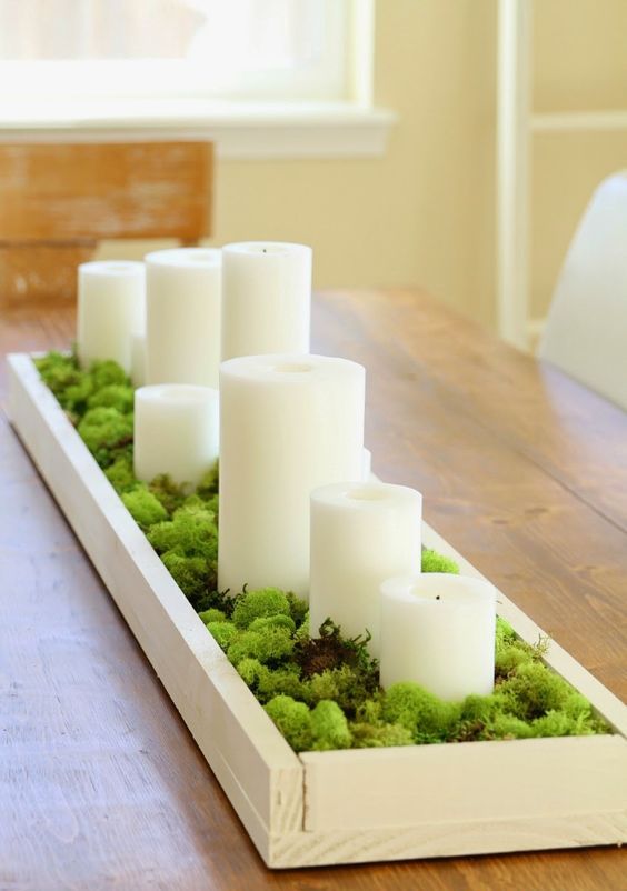 a moss centerpiece with pillar candles in a box is a great idea for any party
