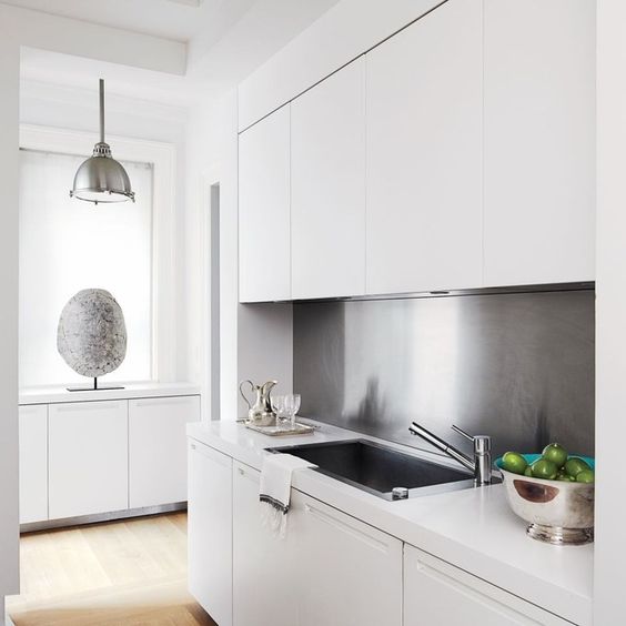 a stainless steel backsplash, a matching lamp and other touches add style to this small kitchen