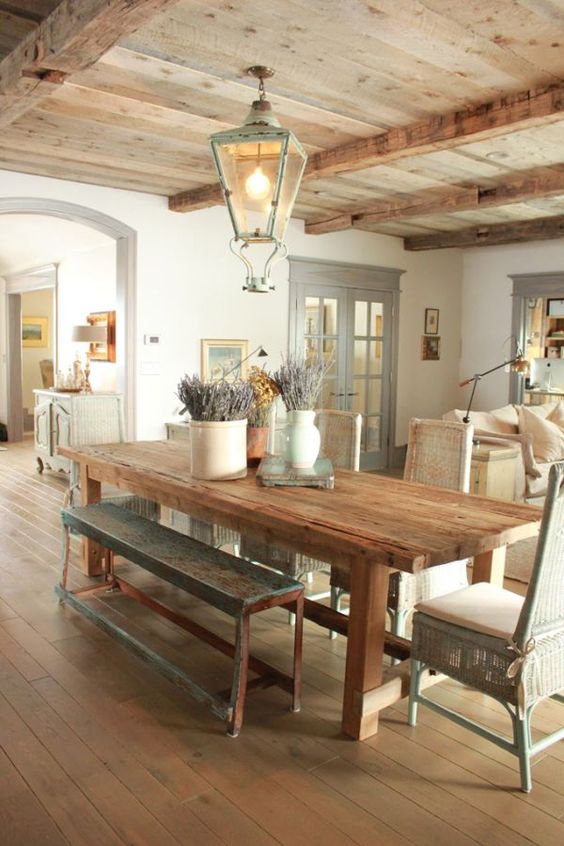 a Provence-styled dining room with a reclaimed wooden ceiling with beams and matching furniture