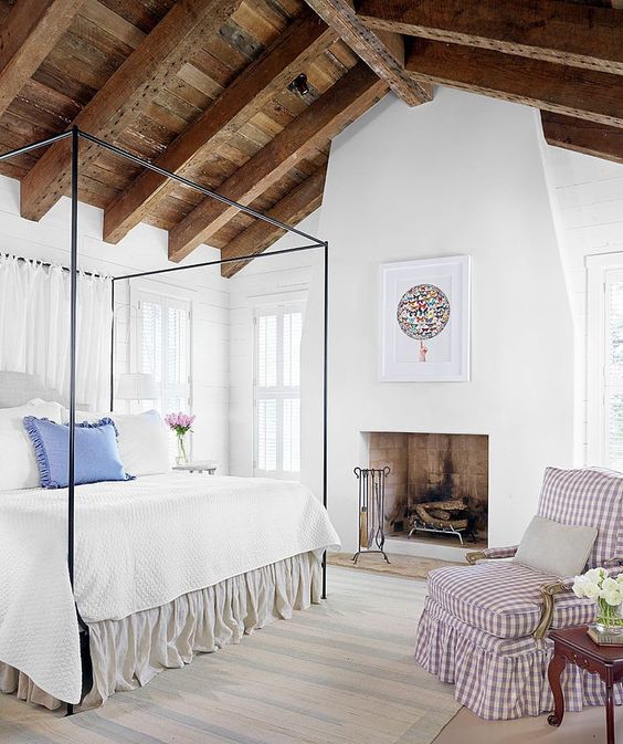 a rustic ceiling of weathered wood with beams makes this cozy country-styled bedroom complete