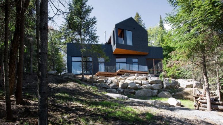 This unique black chalet is located in the forest and has views of the lake, it's built for siblings who have separate but intersecting home parts