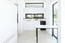 02 The kitchen features white cabinets and windows as a backsplash and over the cabinets to fill the space with light