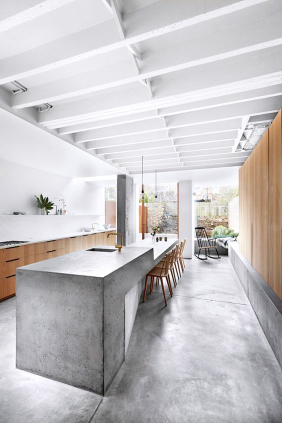 03 A Sculptural And Long Concrete Kitchen Island Features A Dining Space On One End 