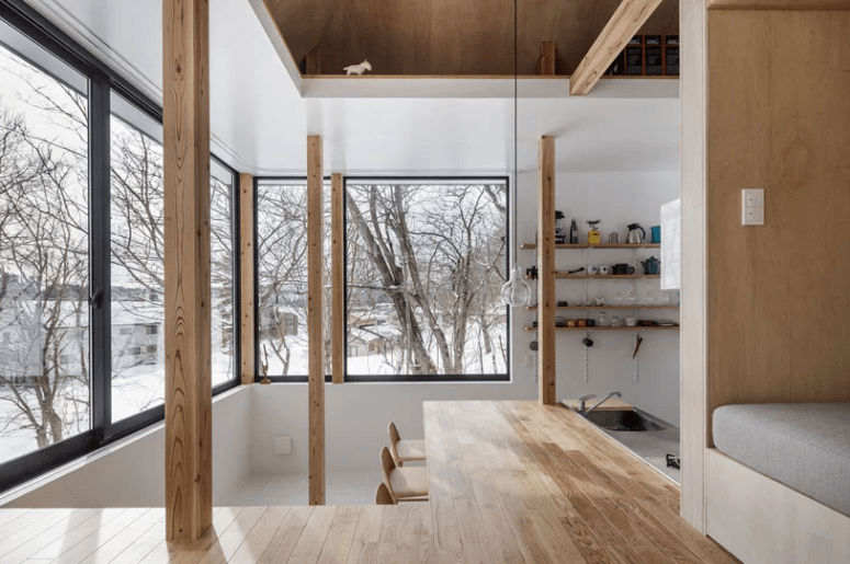 The kitchen features extensive glazing and a corner wooden table for cooking and dining