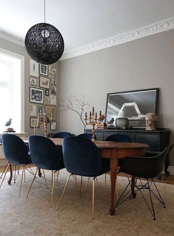 an antique dining table and black velvet upholstered chairs on gilded legs for a personalized feel