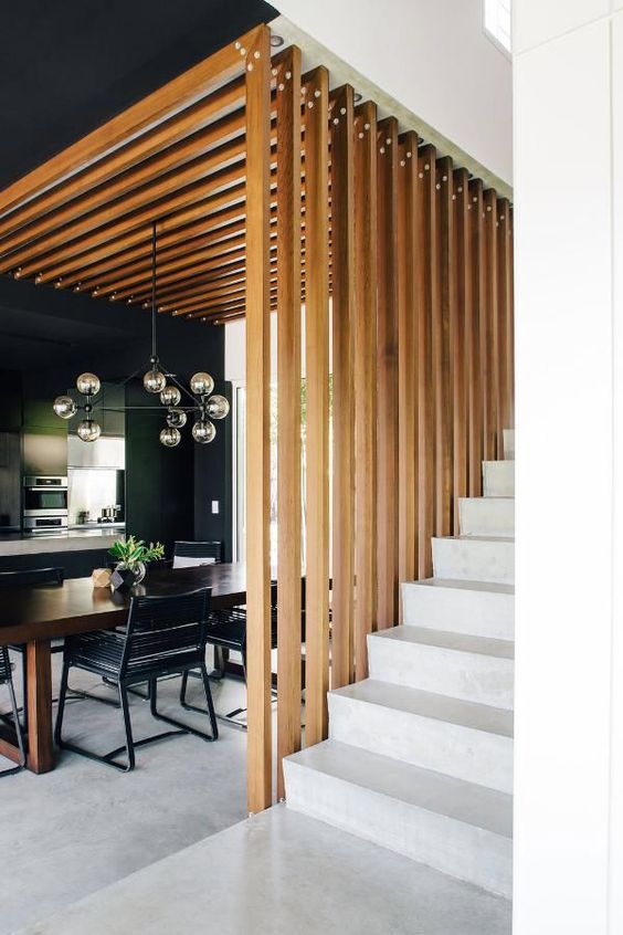 a dining space wraped in a vertical wooden plank screen on one side and from above that makes it a design feature