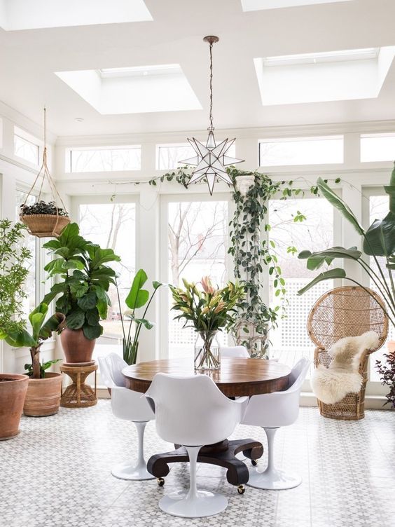 a round vintage table on casters and modern white chairs for a sunroom dining zone