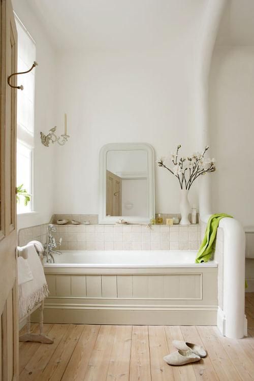 a cozy natural bathtub nook with neutral wood on the tub and matching tiles on the backsplash