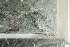 07 a green marble wall and a covered bathtub with brass fixtures create a really refined and luxurious space