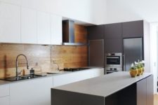 07 a minimalist kitchen with white sleek cabinets and a warm wood panel backsplash plus an additional glass screen in the cooker zone