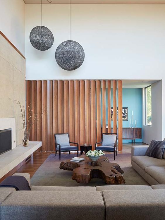 a modern space with a honey-colored wooden plank screen that separates the living room from the entryway