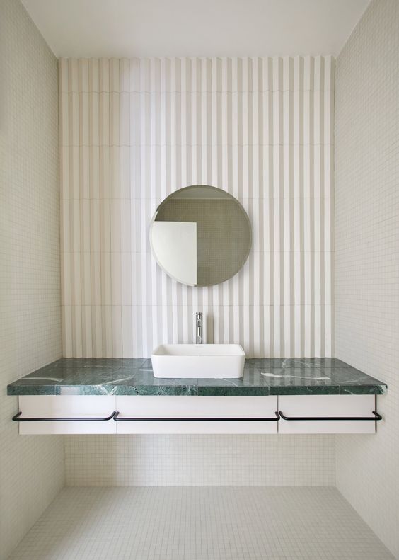 a bathroom vanity with a green marble countertop and a laconic white sink for a contemporary space