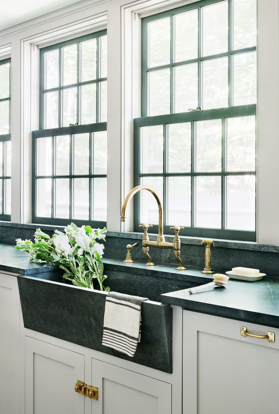 a dark stone sink and a green marble countertop with brass fixtures makes a bold and stylish statement