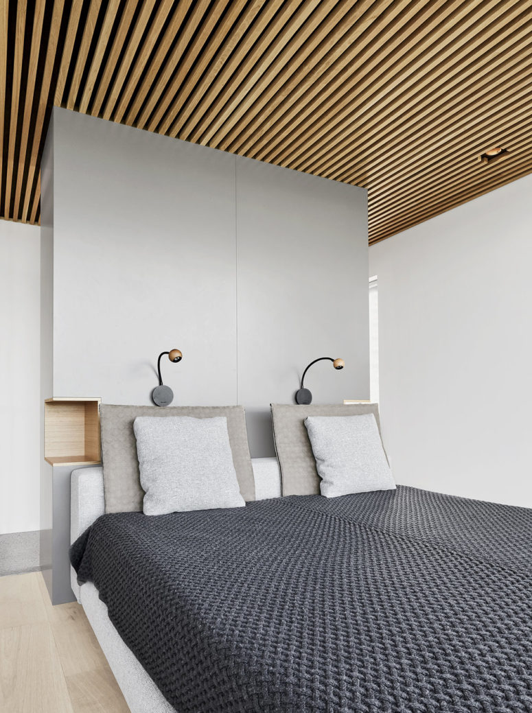 cool built in nightstand The master bedroom is done with an upholstered bed and a sleek grey headboard with built-in nightstands