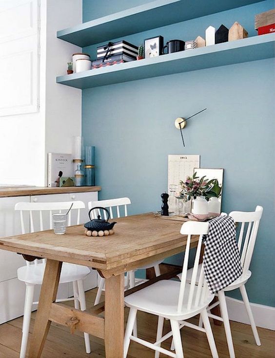 a serenity blue wall with a couple of shelves refreshes this dining nook and makes it cool