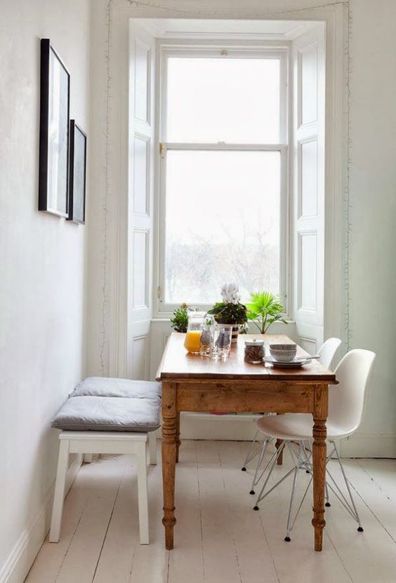 an antique rustic table and white modern chairs plus a bench for a cozy dining space
