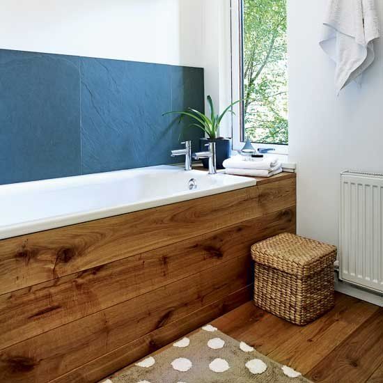 large slate tiles used as a bathtub backsplash create a bold contrast to light-colored wood