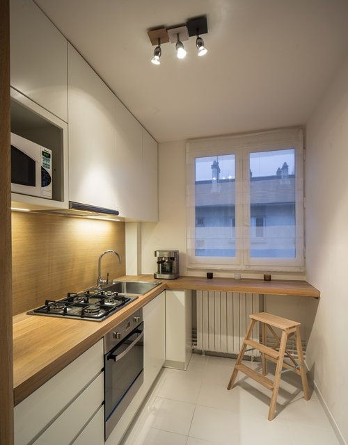 a tiny minimalist kitchen with a wood panel backsplash and countertop, the backsplash is additionally covered with glass