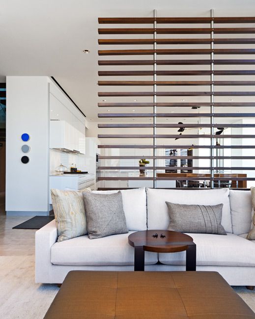 a modern horizontal wooden plank screen lets light and air but divides the kitchen and the living room visually