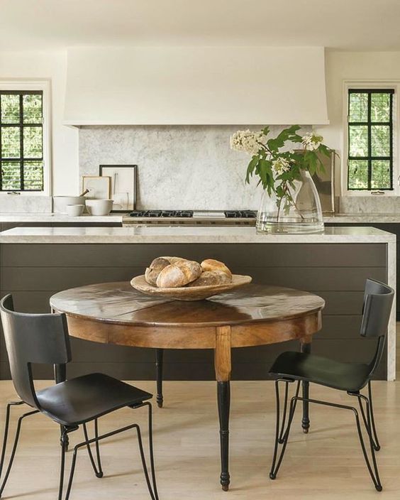 a vintage round dining table with black legs and black modern industrial chairs to create a softer look