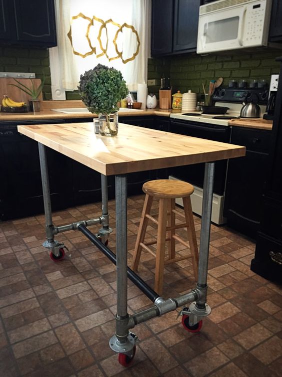 a portable industrial kitchen island of metal pipes on casters and a butcher block as a top can be DIYed by you