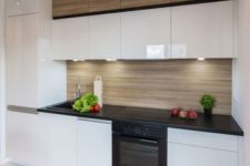 14 sleek glossy white cabinets plus a light-colored wood backsplash and matching upper cabinets
