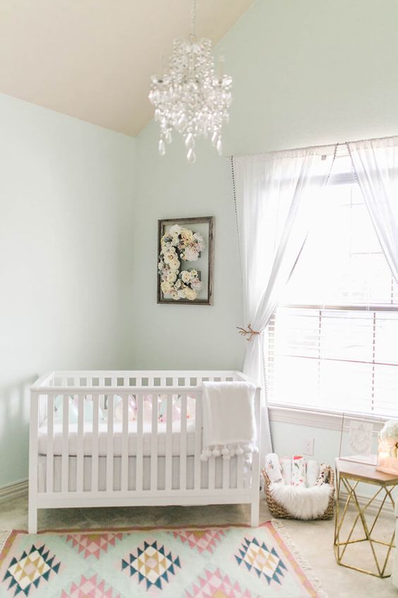 a large window, sheer drapes and a crystal chandelier for a welcoming and airy feel