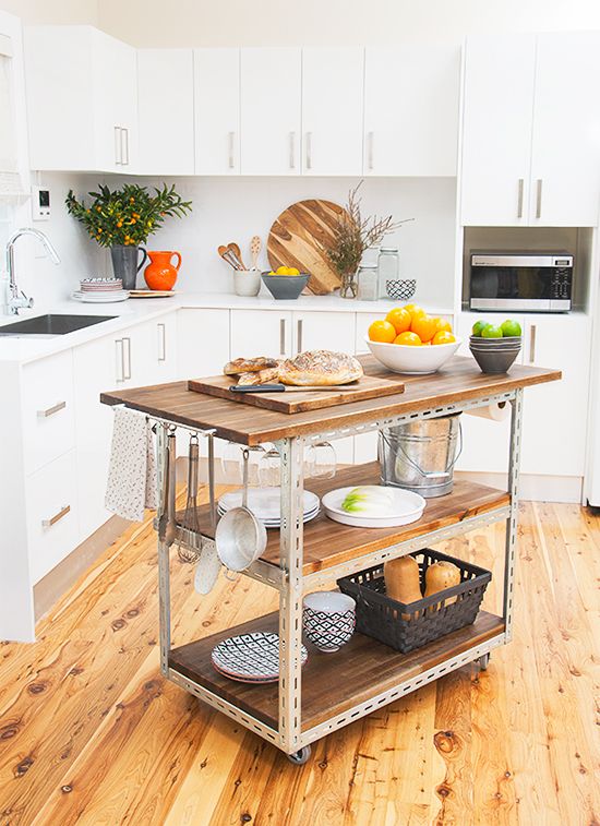 a simple industrial kitchen island of steel and reclaimed wood on casters features two open shelves