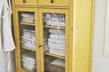 16 a yellow cabinet with glazing is a great idea to store towels in a rustic bathroom