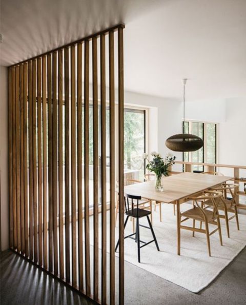 a wood plank space divider that separates the dining space from the kitchen and lets light in