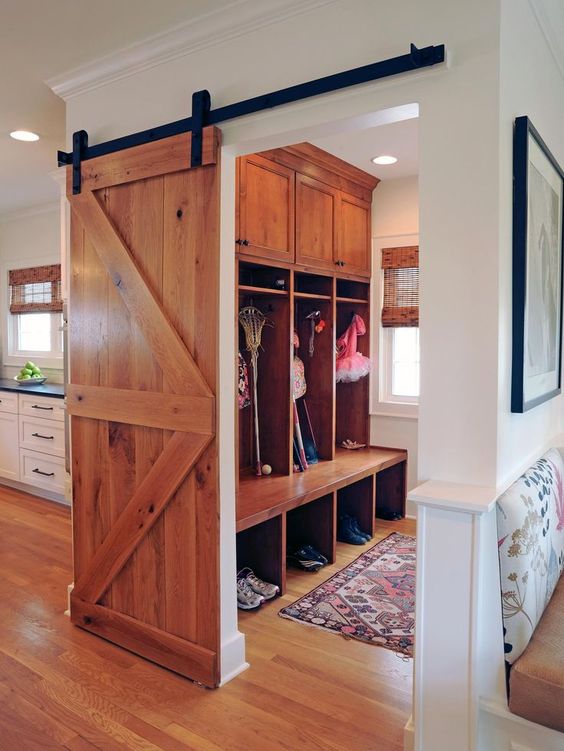 a light-colored sliding barn door can be used to hide a small mudroom or another functional space