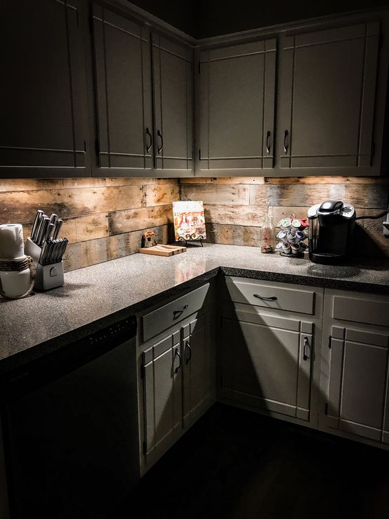 a rustic off white kitchen with a stone countertop and a reclaimed wood backsplash plus additional lights