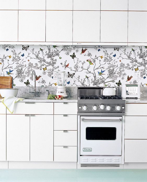to avoid a boring look in an all-white kitchen, rock a colorful wallpaper backsplash with butterflies and birds