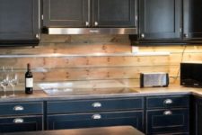 23 vintage black cabinets, silver handles and a wooden plank backsplash with an additional glass screen for protection