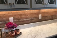 24 vintage grey cabinets, a marble countertop and a wooden plank backsplash for a less formal look