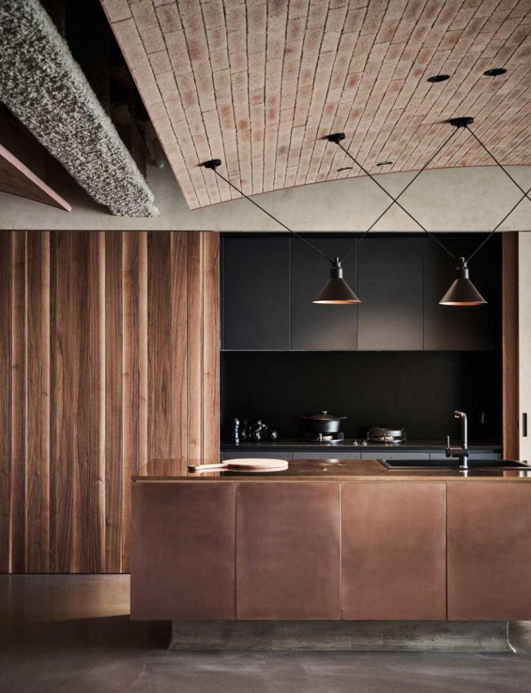 industrial looking kitchen island The kitchen is done with black sleek cabinets that can be hidden with wooden sliding doors and a copper clad kitchen island