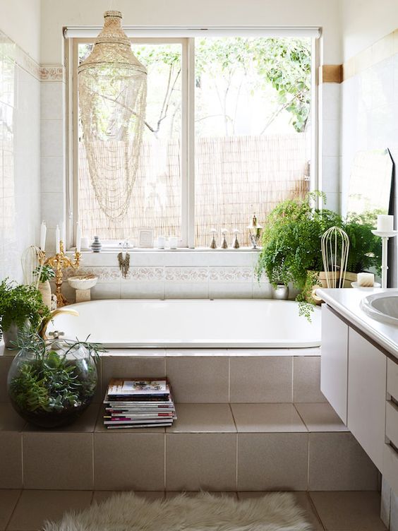 a boho chic bathroom with potted greenery, a creative chandelier, candle holders and a faux fur rug