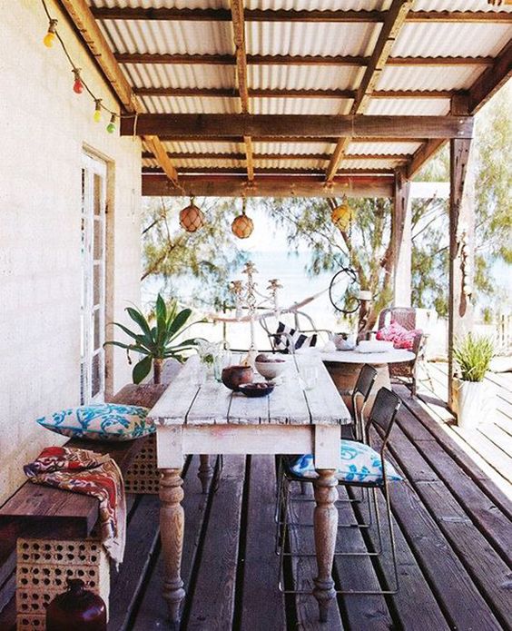a boho colorful porch with a dining zone and a sitting one with lanterns and colorful textiles