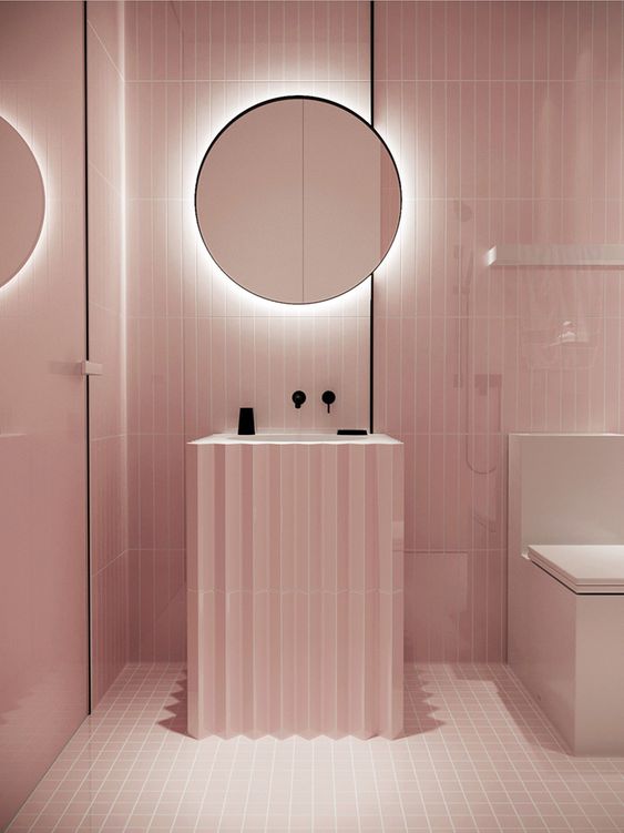 a minimalist light pink bathroom with black touches for depth and a mirror with built-in lights