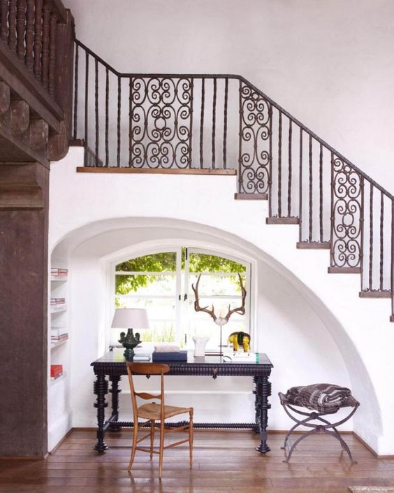 an arched under the stairs home office nook with a rounded window to enjoy the views