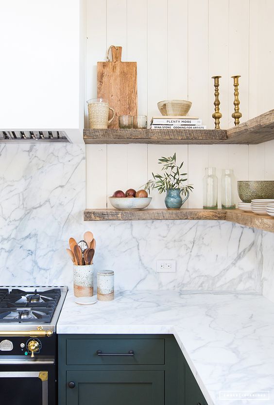 sage green cabinets, a white and grey marble backsplash and countertops and raw open wooden shelves