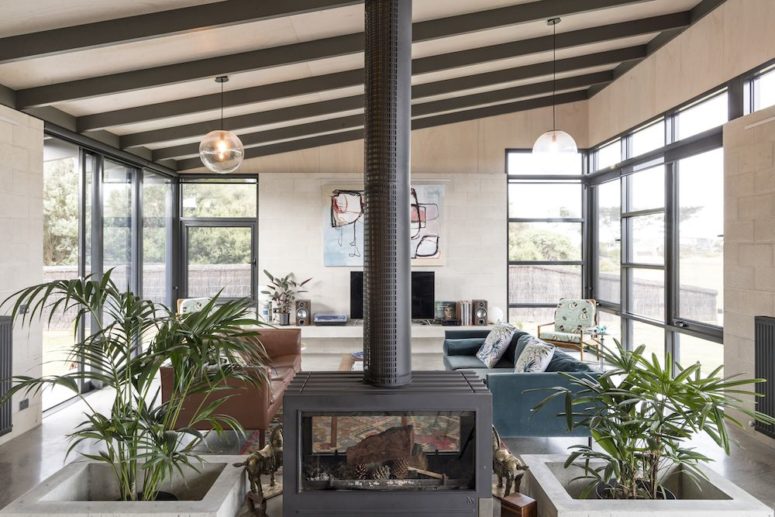 large fireplace in a middle of a room Expsoed beams highlight the ceiling, a large fireplace not only separates the spaces but also brings coziness to both of them