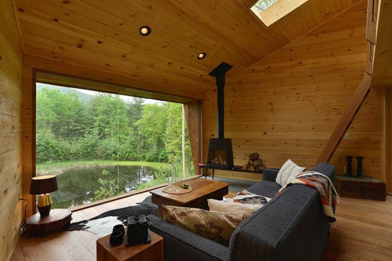 The living space features a grey sofa, some wooden side tables and a metal hearth, a glazed wall features an amazing view The living space features a grey sofa, some wooden side tables and a metal hearth, a glazed wall features an amazing view